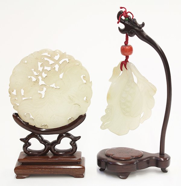 Two Chinese Hardstone Carvings: (lot of 2) Chinese pierced hardstone carvings, one of foliage form suspended from a wood stand; the other a roundel reticulated with a pair of bats and peaches, the frosted white matrix with opaque fl