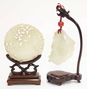 Two Chinese Hardstone Carvings: (lot of 2) Chinese pierced hardstone carvings, one of foliage form suspended from a wood stand; the other a roundel reticulated with a pair of bats and peaches, the frosted white matrix with opaque