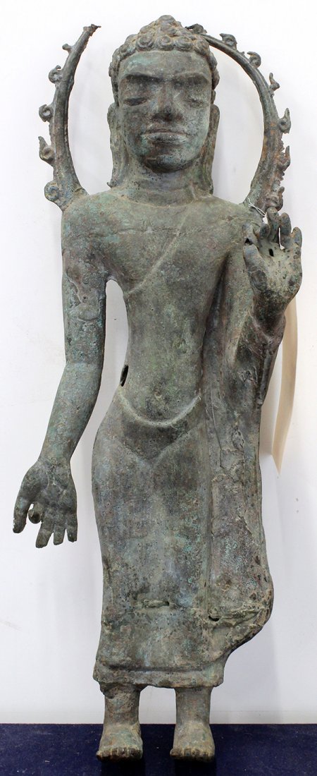 Southeast Asian Standing Buddha: Southeast Asian metal sculpture, of a standing Buddha with a serene face and back by a mandorla, 19.75"h. Provenance: From the estate of Edward Gerber