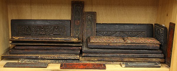 Group of Southeast Wood Panels/Covers: (lot of 22) One shelf of Southeast Asian wood panels, some of the panels are covers of Buddhist manuscript, and others are stamps, largest: 26.5"w, Provenance: From the estate of Edward Gerber