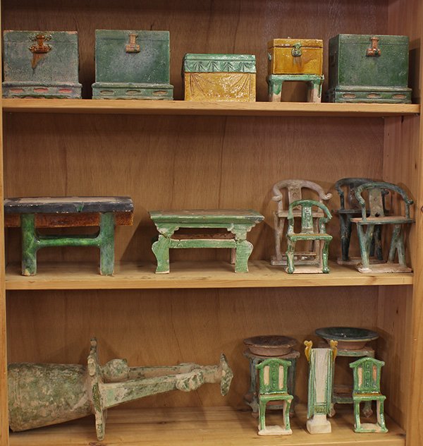 Chinese Glazed Ceramic Funerary Goods: (lot of approx 19) Three shelves of Chinese glazed ceramics, the mingqi (funerary goods) include trunks, chairs, tables, wash stand; together with a Han-style green glaze well, 19.5"h; Provenance: Fro