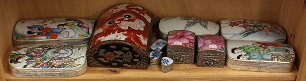 Chinese Boxes with Porcelain Fragments: One shelf of Chinese porcelain inset boxes, one with a red lion set onto a lacquered wood box; the rest with metal boxes, largest: 9.5"; Provenance: From the estate of Edward Gerber