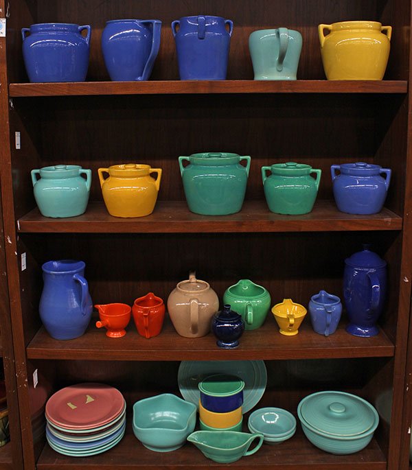 Art pottery by Fiesta, Bauer, and Pacific: Four shelves of art pottery by Fiesta, Bauer, and Pacific, including bean pots, plates, pitchers, teapot, in colors including orange, blue, green, and yellow