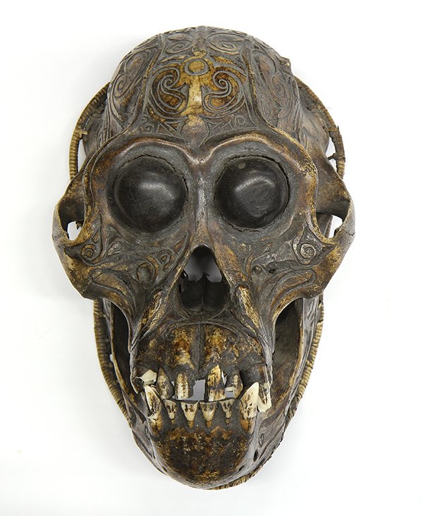 Asian Skull of a Primate: Asian carved skull of a primate, inset with wooden bulging eyes below the skull carved with scrolling patterns, the edge wrapped in rattan, 9.5"h. Provenance: From the estate of Edward Gerber