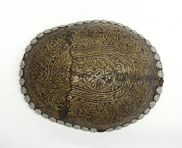 Sino-Tibetan Skull Cup: Himalayan skull cup, carved with the Eight Buddhist Treasures accented by foliage, the rim heightened with repousse skull appliques and a silver liner to the interior, 6.75"l. Provenance: From the est
