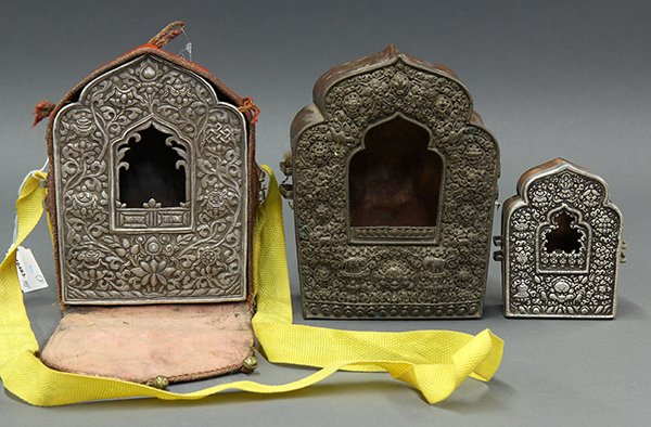 Three Sino-Tibetan Repousse Gau: (lot of 3) Himalayan repousse copper and metal gau (portable shrine), each of the shaped apertures framing the Eight Buddhist Treasures in repousse (one with felt cover), largest: 7.5"h. Provenance: F
