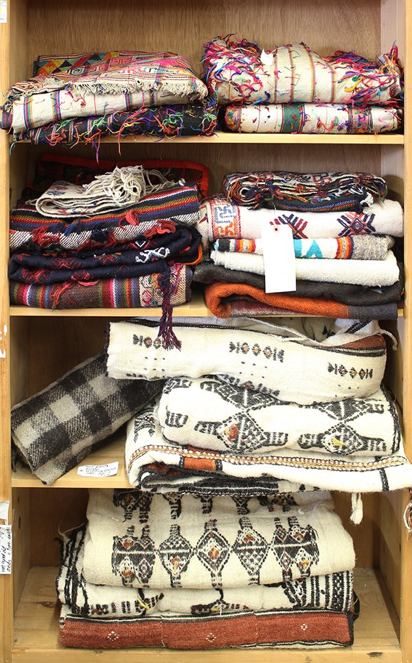 (lot of approx 21) Four shelves of ethnographic: (lot of approx 21) Four shelves of ethnographic textiles, including Tibetan cotton embroideries, Fulani Wedding blankets from Mali, and Nepalese wool blankets. Provenance: From the estate of Edward Ge