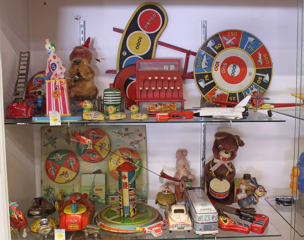 Two shelves of tin lithograph toys: (lot of approximately 30) Two shelves of tin lithograph toys, including a Honeymoon Express by Marx having two planes, a mechanical target toy with three whirling targets depicting different war plane
