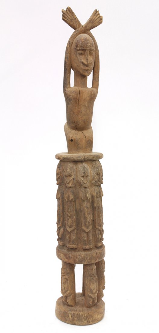 Dogon style, Mali carved wood sculpture: Dogon style, Mali carved wood sculpture, the double pedestal stool carved with ancestral figures, and surmounted by a male figure with hands crossed above head, 27"h. Provenance: From the estate of Ed