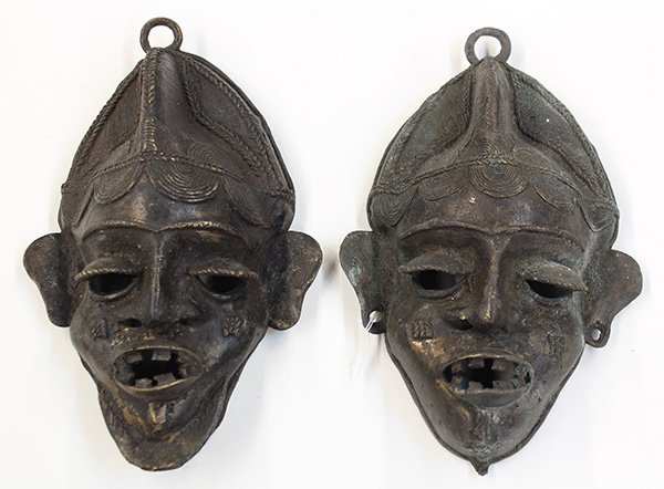 West African decorative metal masks: (lot of 2) West African decorative metal masks, each having facial scarification and a stylized coiffure, each: 10"h. Provenance: From the estate of Edward Gerber