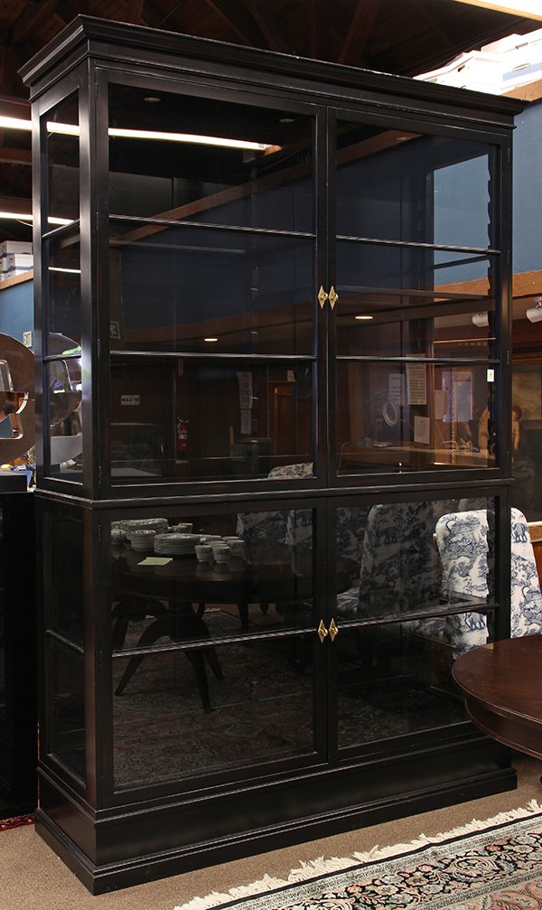 Monumental Moderne display cabinet: Monumental Moderne display cabinet, executed in ebonized wood, in two parts, each having two doors opening to a fixed shelf interior and rising on a molded base, 104"h x 68"w x 22"d