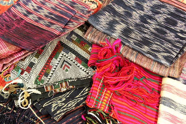 (lot of 22) Associated group of textiles including: (lot of 22) Associated group of textiles including Balinese and South East Asian examples, ikat and batik, together with woven place mats. Provenance: From the estate of Edward Gerber