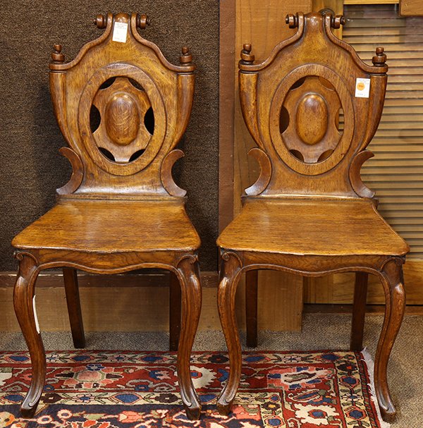 Continental hall chairs: (lot of 2) Continental hall chairs, 19th century, executed in oak, each having a carved crest, above the pierced back, and rising on cabriole legs, 34.5"h