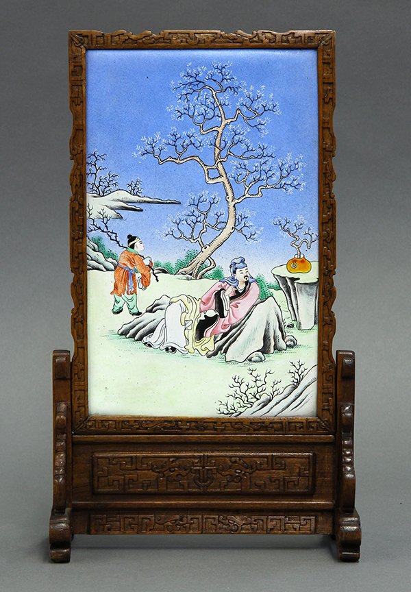 Chinese Enameled Table Screen: Chinese small table screen, inset with an enameled metal plaque decorated with a reclining scholar along with an attendant, backed by a flowering tree, the wood frame carved with dragons, overall: 12.