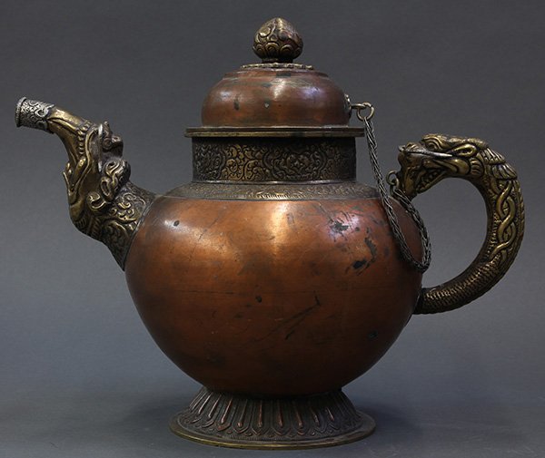 Himalayan Copper Bhumpa/Ewer: Himalayan large copper ewer (bhumpa), the ovoid copper body bracketed by a makura spout and opposing dragon-fish form loop handle, a lotus form lid set above the ewer, 10.75"h. Provenance: From the es