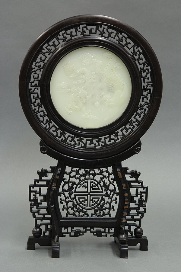 Chinese Jade Dragon Table Screen: Chinese jade and wood table screen, the circular plaque carved with meandering dragon and phoenix, reversed with a twenty character colophon heightened with gilt, inset within a circular wood frame ac