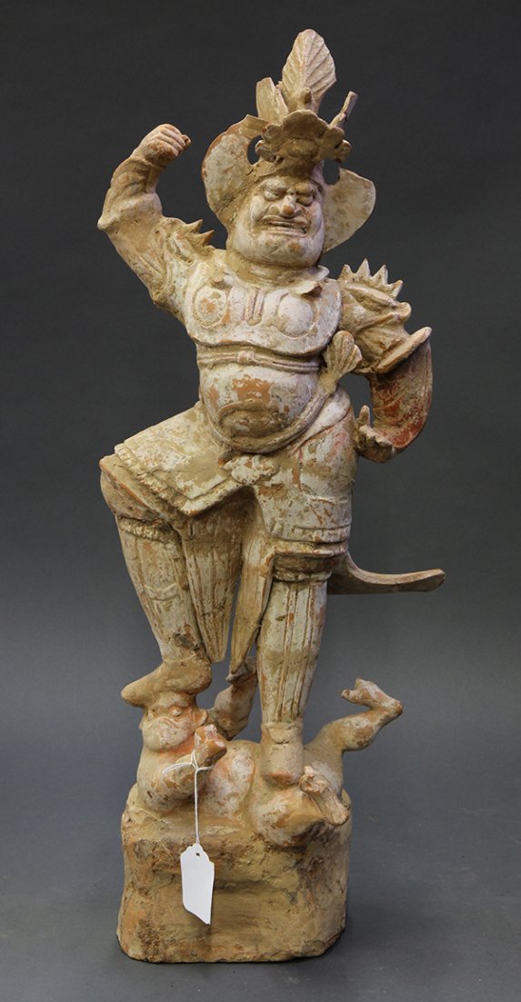 Chinese Tang-style Guardian: Chinese Tang-style pottery guardian figure, the figure in military garb in stance above a demon, 25.75"h. Provenance: From the estate of Edward Gerber