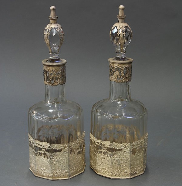 Pair of Continental crystal stoppered decanters: Pair of Continental crystal stoppered decanters, each faceted bottle mounted with a repousse silverplate sleeve depicting Roman soldiers, 12"h
