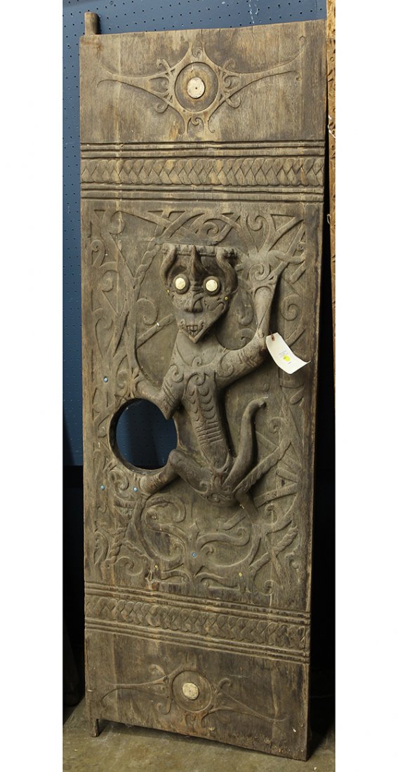 Southeast Asian carved door: Southeast Asian carved door, the heavy decorative plank featuring a pronounced zoomorph figure set with shell eyes, 76"h x 26"w. Provenance: From the estate of Edward Gerber
