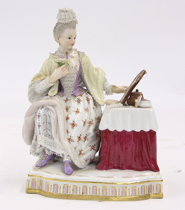 Meissen porcelain figural group: Meissen porcelain figural group, depicting a lady at toilette, dressed in 18th century period attire, seated at a vanity table and gazing into a looking glass, depicted wearing a lace cap, a gold cros