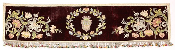 Continental embroidered textile banner: Continental embroidered textile banner, 19th century, executed in applique and metal thread couching on burgundy velvet, centering a familial crest, surrounded by a polychrome floral wreath and flanke