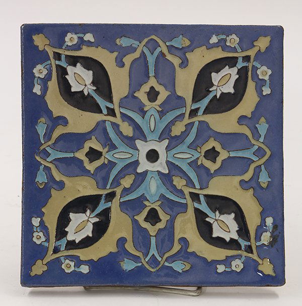 Large Arts and Crafts California Faience tile trivet: Large Arts and Crafts California Faience tile trivet, depicting a stylized geometric motif in taupe, turquoise and black on a sky blue ground, impressed mark verso, 8"dia.
