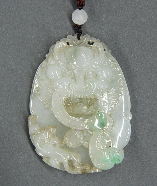 Chinese Jadeite Toggle, Dragon: Chinese jadeite toggle, carved with a dragon head along with a chilong, coins and ruyi scepter which has two splashes of green in contrast with the white matrix, the back carved with scrolls in low re