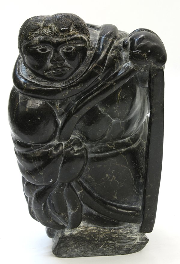 Inuit soapstone figural carving of a hunter,executed in: Inuit soapstone figural carving of a hunter,executed in black stone with white veining, the figure leans forward and his hand rests on a bow, retains a paper label but unsigned, 13"h x 8"w x 8"d