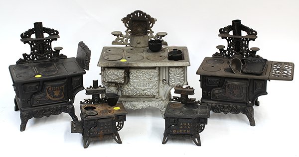 (lot of 11) Toy cast iron stoves and accessories: (lot of 11) Toy cast iron stoves and accessories, including a Kenton Acme stove having (6) burners, a water reservoir, and a cast back piece with warming plates and a shelf, 13"h x 11"w; a Crescent, f