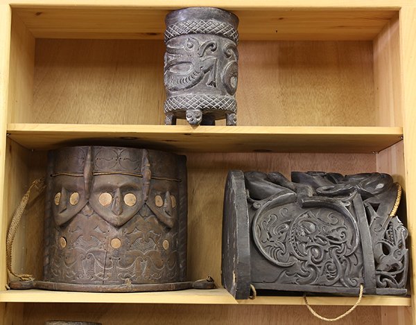 (lot of 3) Dayak, Indonesian decorative baby carriers,: (lot of 3) Dayak, Indonesian decorative baby carriers, made in the 20th century for trade, each carved of demilune form with mythological beings; together with a cylindrical footed vessel. Provenance: