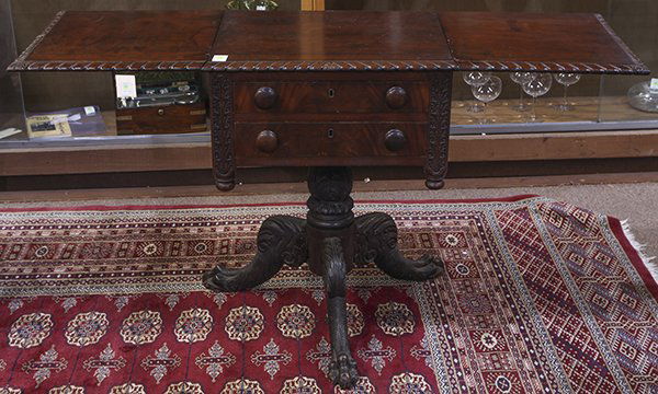 American Empire drop leaf work table: American Empire drop leaf work table, 19th century, executed in mahogany, having a rectangular top with gardrooned edge, above the two drawer case having turned pulls, and flanked by florifom carved b