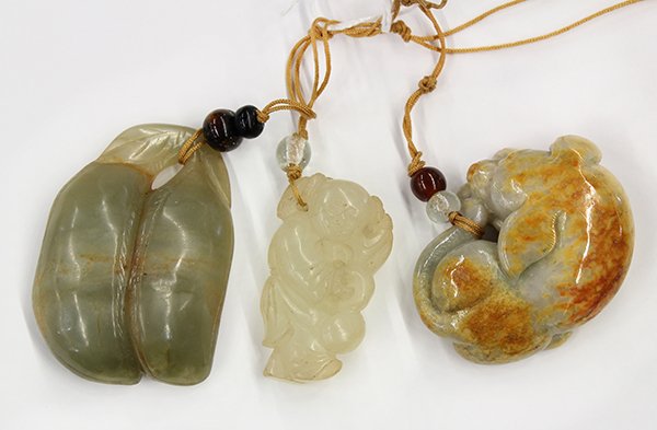 Three Chinese Jade Toggles: (lot of 3) Chinese jade toggles; the first of a child carrying a double gourd and a lingzhi sprig; the second of a recumbent dog with russet inclusions; the last with pea pods of grey green color, 2.2