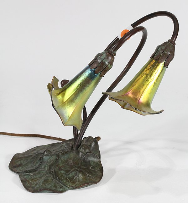 Lily-form two light table lamp: Lily-form two light table lamp, having two curved stems with gold aurene shades bearing etched L.C.T mark, the bronze base in the form of overlaping lily pads, bears impressed 'Tiffany Studios New Yor