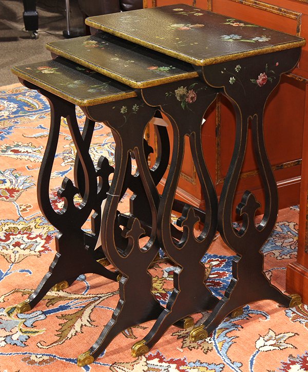 Regency style ebonized and gilt nesting tables, having: Regency style ebonized and gilt nesting tables, having a polychrome floral decorated top, above lyre supports, and rising on arched scroll legs, largest: 28"h x 21"w x 12.5"d. Provenance: From the Nan