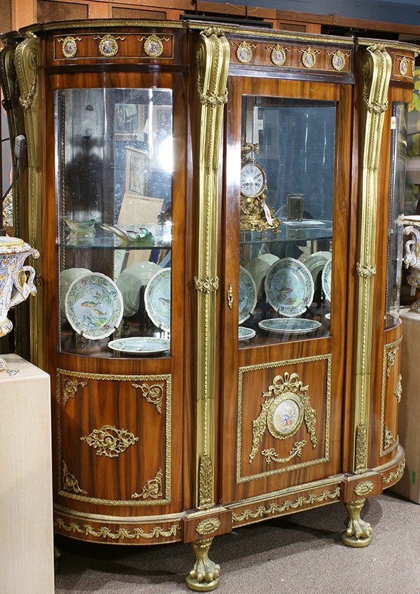 Louis XVI style ormolu mounted lighted vitrine: Louis XVI style ormolu mounted lighted vitrine, the shaped top having a gilt decorated border accented with Sevres style porcelain inset plaques depicting Middle Eastern courting couples, continuing t