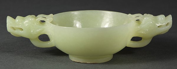 Chinese Jade Cup with Dragon Handles: Chinese celadon jade cup, the shallow cup bracketed by a pair of dragon form handles, and raised on a low foot ring, 5.5"w