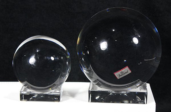 (lot of 2) Baccarat crystal balls: (lot of 2) Baccarat crystal balls, the clear spheres resting on custom square bases, marked Baccarat, largest sphere 5.5"dia