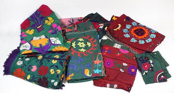 (lot of 9) Indian or Pakistani embroidered textiles in: (lot of 9) Indian or Pakistani embroidered textiles in the style of suzanis, including (2) coverlets having polychrome flowers embroidered on green grounds with applied purple fringe, (1) green coverl