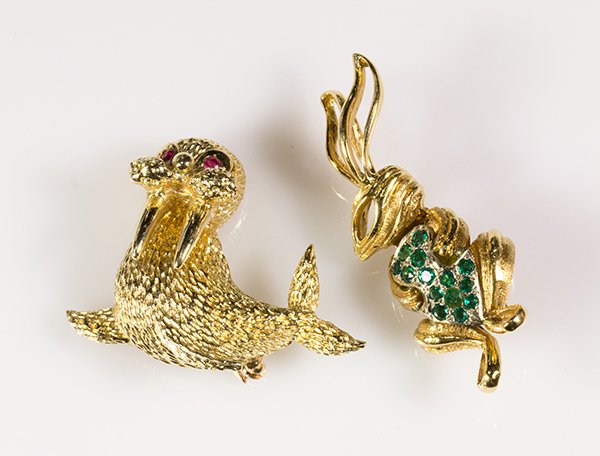 (lot of 2) Yellow gold animal pins: (lot of 2) Yellow gold animal pins, comprised of one 18k yellow gold rabbit pin set with one natural and (13) synthetic emeralds, 2" x 3/4" and one 14k yellow gold walrus pin set with ruby eye accents