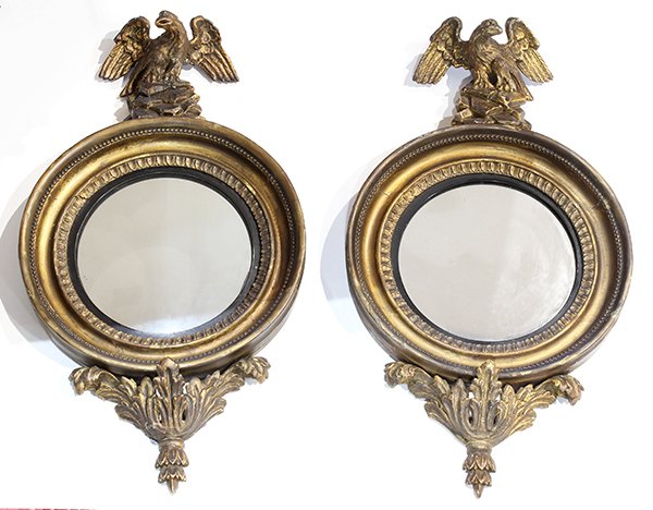 Pair of Regency style gilt wood convex mirrors, second: Pair of Regency style gilt wood convex mirrors, second quarter 19th century each having a figural finial depicting an eagle, above the molded and beaded frame, centering the circular looking glass, 21