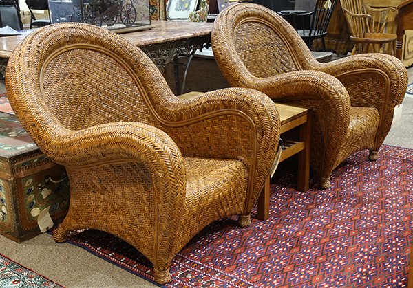 Pair of rattan arched back club chairs, each having a: Pair of rattan arched back club chairs, each having a loose cushion centering the sloped arms, and rising on ball feet, 36"h; Provenance: From the Nantucket, MA estate of Richard Mellon Scaife