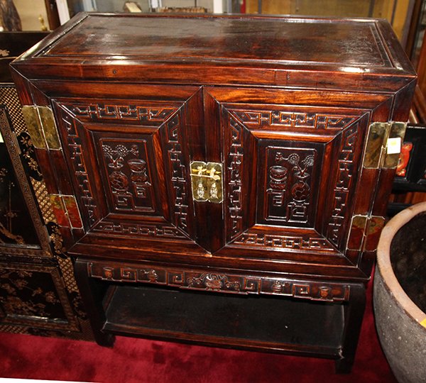 Chinese Two Section Wood Cabinet, Scholar's Items: Chinese wooden cabinet on stand, the hinged double door carved with flowers and antiques, fitted with double fish form metal handles, both sides with shou pattern and bats, raised on a separate tiered