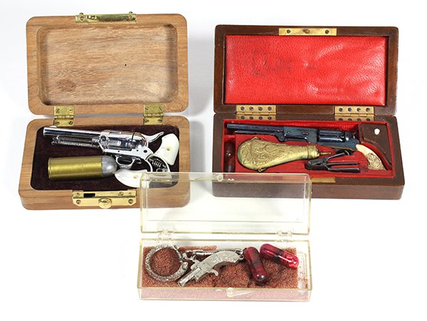 (lot of 3) Miniature cap pistols, comprising a cased: (lot of 3) Miniature cap pistols, comprising a cased miniature Colt style revolver fitted with a powder flask, bullet mold and caps, in a satin lined wood case 4.5"l x 2.5"w; a miniature chrome plated