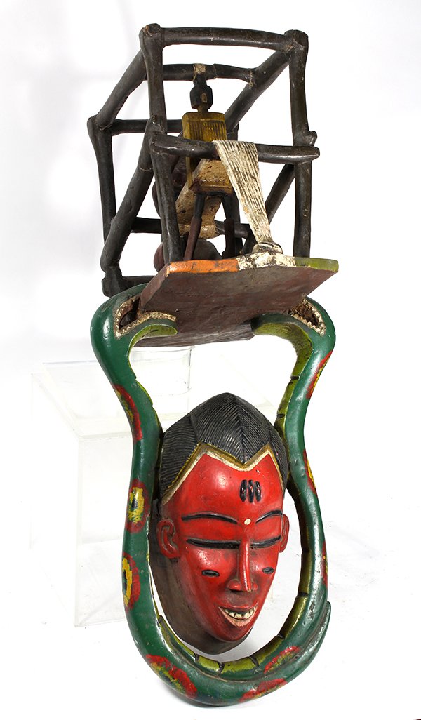 West African decorative parade mask in honor of the: West African decorative parade mask in honor of the character Mami Wata, the face mask flanked by snakes, and surmouned by a seated weaver, 27"l x