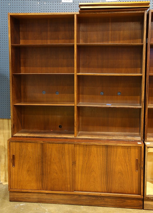 (lot of 2) Danish Modern style book shelves over a: (lot of 2) Danish Modern style book shelves over a cabinet, executed in rosewood, having (8) shelves above a cabinet with sliding doors having inset handles, 77"h x 54"w x 17"d. Provenance: Thomas Liv
