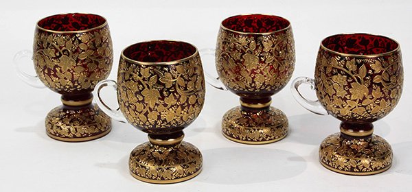 (lot of 4) Moser ruby and gilt handled vessels: (lot of 4) Moser ruby and gilt handled vessels, each having a shaped body with raised gilt floral sprays continuing to the footed base, each: 5"h