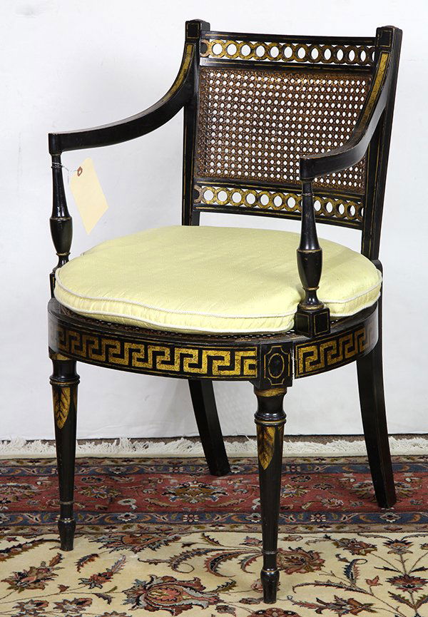 English ebonized and parcel gilt armchair in the: English ebonized and parcel gilt armchair in the Regency taste, late 19th century, having a gilded rinceau crest with caned back flowing to the curved arms rising on urn form stiles, the seat with a y
