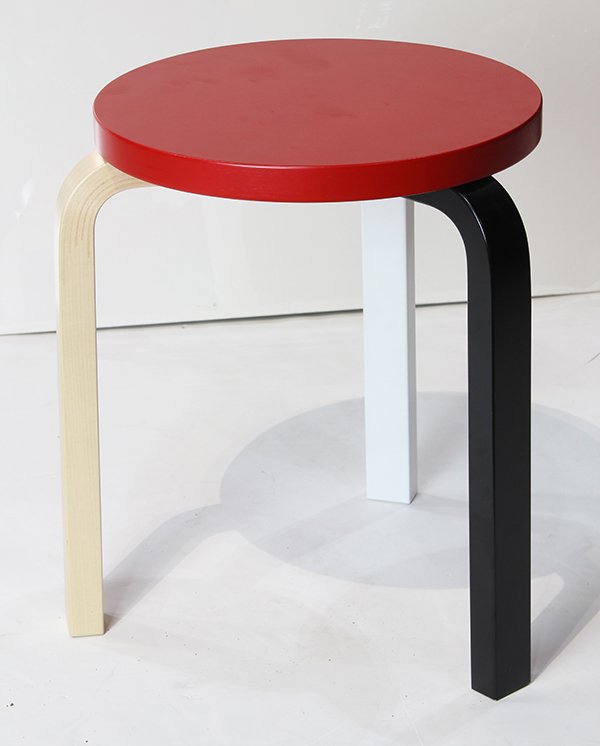 Artek Alvar Aalto Anniversary Colors Stool 60: Artek Alvar Aalto Anniversary Colors Stool 60, having a crimson top rising on shaped legs in three colors, one in blonde, one in black, one in white, 17.25"h