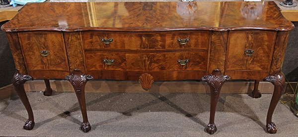 English mahogany sideboard, early 20th century, having: English mahogany sideboard, early 20th century, having a shaped top above a serpentine case with two drawers flanked by two convex doors opening to three pull-out shelves, centering a shell and acanth
