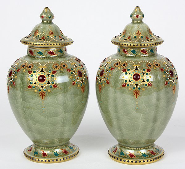 Pair of KPM jeweled porcelain lidded urns: Pair of KPM jeweled porcelain lidded urns, each having a tapered form in pistachio green accented with gilt scrolls and raised enameling, and rising on a circular base, each signed with underglaze sce